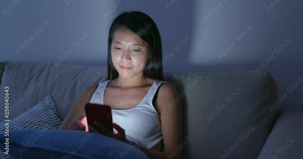 Woman send sms on cellphone at home in the eveneing Woman send sms on cellphone at home in the eveneing