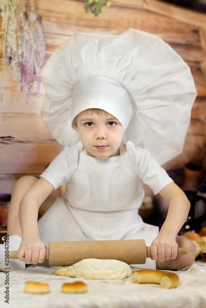 the little boy is preparing cake and pancakes. Dressed like a chef child dough prepares food. the little boy is preparing cake and pancakes. Dressed like a chef child dough prepares food.