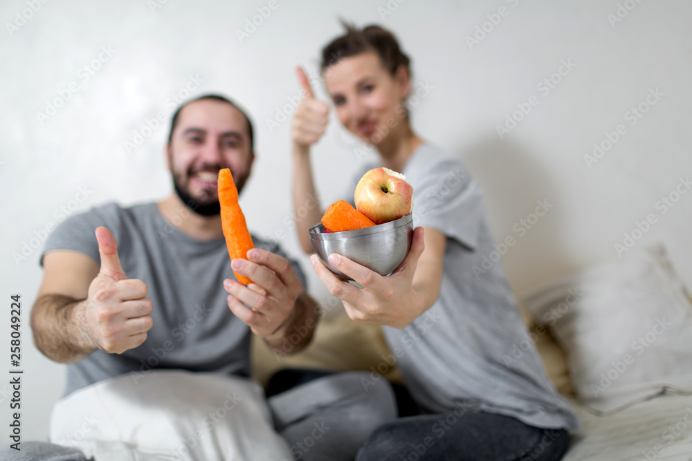 Happy couple holds a plate of vegetables in their hands. White background. Happy couple holds a plate of vegetables in their hands. White background.