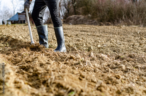 Male farmer working the soil, wearing rubber boots