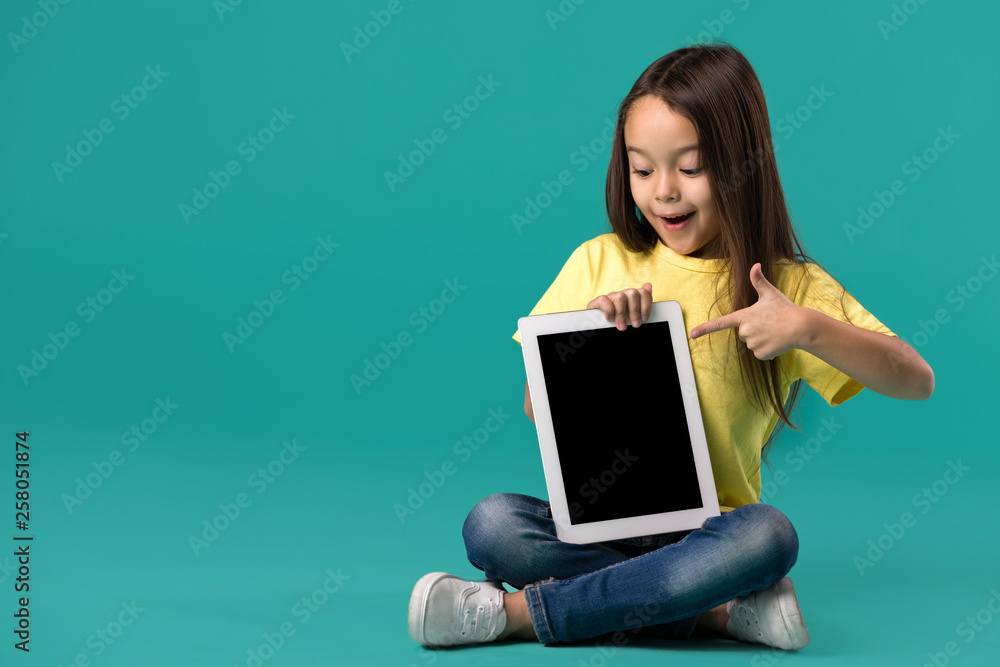 cute little child girl holding blank tablet computer on blue background cute little child girl holding blank tablet computer on blue background