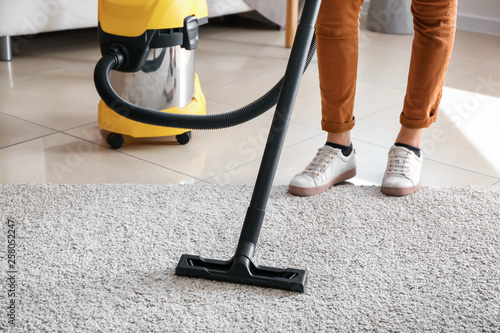 Woman cleaning carpet with hoover at home