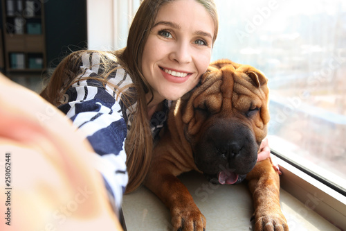 Bild auf Leinwand Woman taking selfie with her cute funny dog near window