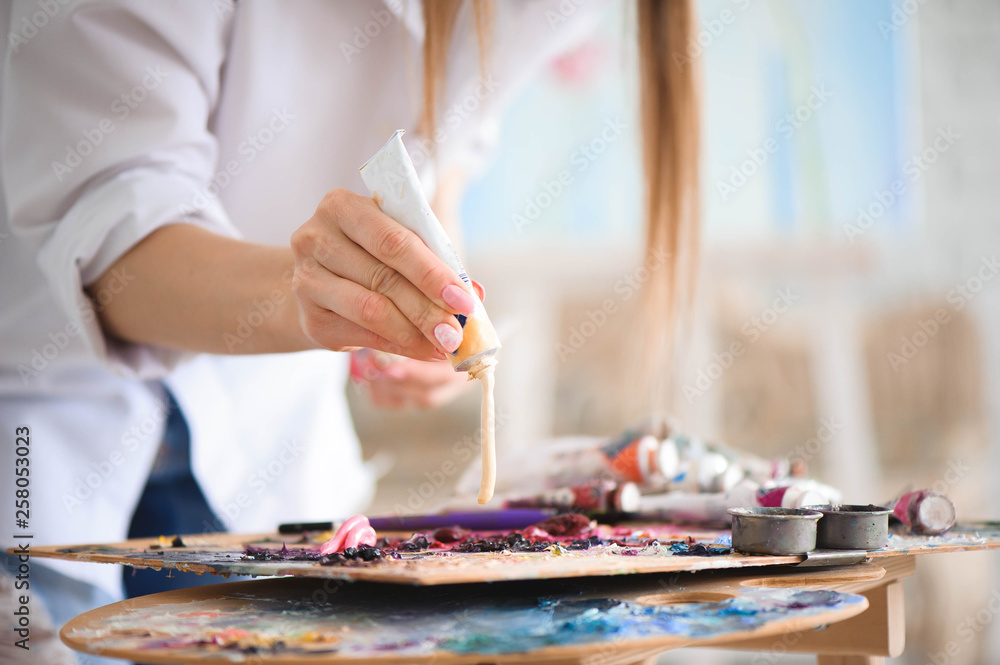 Closeup of paintbrush in woman hands mixing paints on palette Closeup of paintbrush in woman hands mixing paints on palette