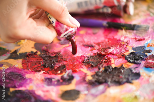 Closeup of paintbrush in woman hands mixing paints on palette