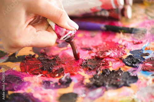 Closeup of paintbrush in woman hands mixing paints on palette