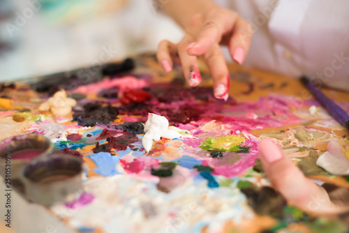 Сute girl artist paints on canvas painting on the easel. Model in the studio