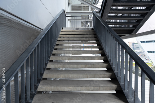 Empty concrete staircase with black steel handrail.