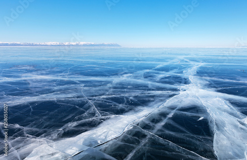 Typical winter landscape of frozen lake Baikal. Endless fields of smooth blue ice with cracks receding into the distance. Cold natural background