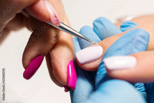 Hardware Manicure using electric device machine. procedure for the preparation of nails before applying nail polish. Hands of Manicurist in blue gloves and Nails of Client. Woman In Beauty Salon. Nail