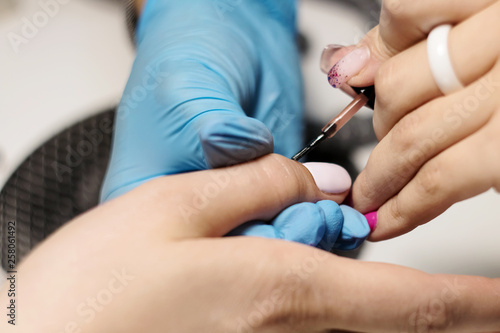 Hardware Manicure using electric device machine. procedure for the preparation of nails before applying nail polish. Hands of Manicurist in blue gloves and Nails of Client. Woman In Beauty Salon. Nail