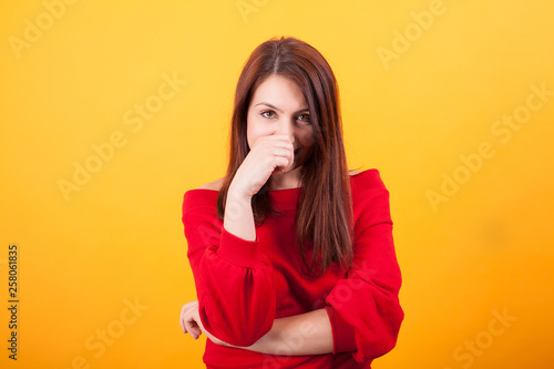 Image of beautiful young woman looking at the camera over yellow background