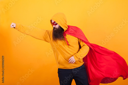 Bearded hipster dressed in superhero costume flying away to save the world ovr yellow background photo