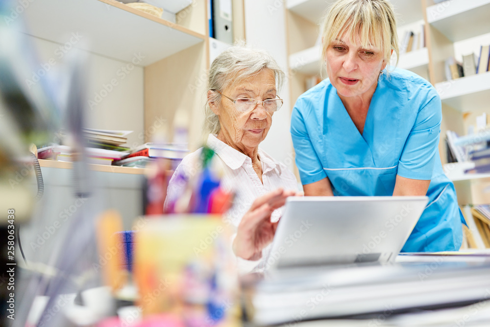 Obraz premium Senior Frau und Pflegehilfe am Laptop