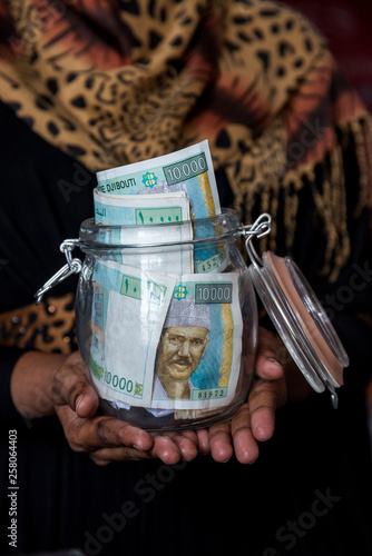 Women holding a jar full of 10,000 Djibouti Francs - Savings