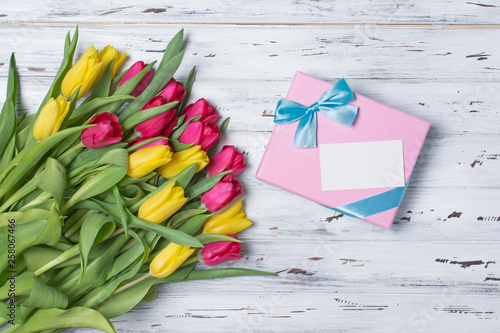 Beautiful bouquet of fresh yellow and pink tulips with gift box and card