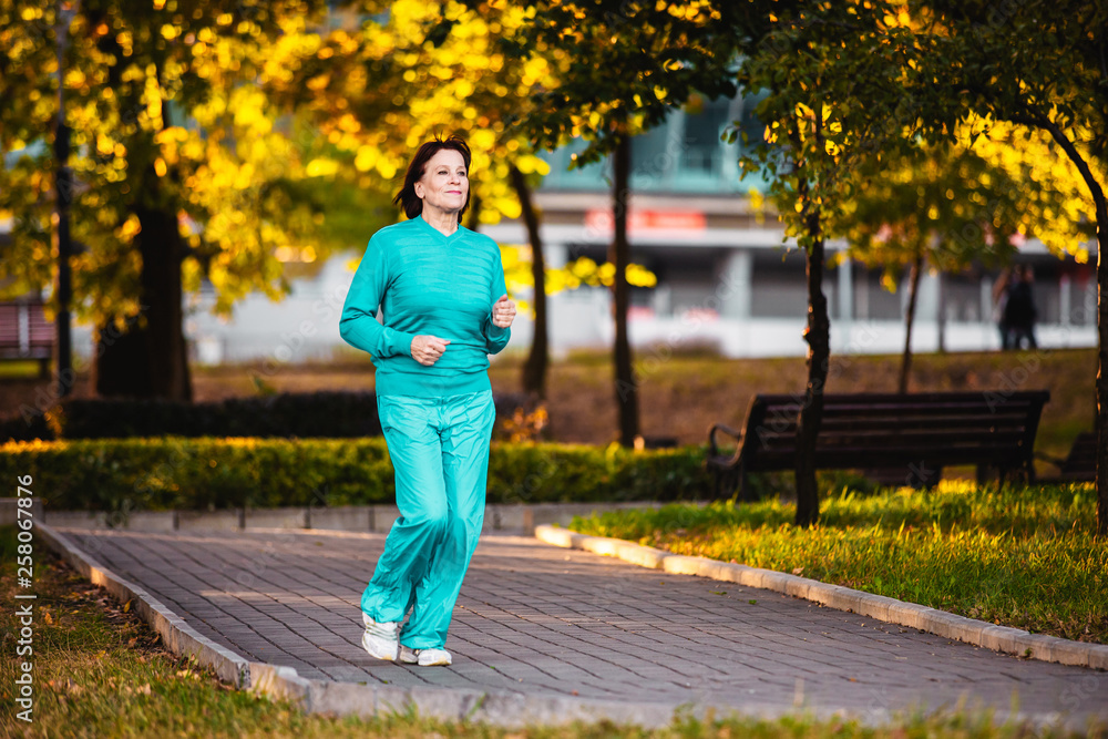 An elderly woman goes in for sports at sunset. An elderly woman goes in for sports at sunset.
