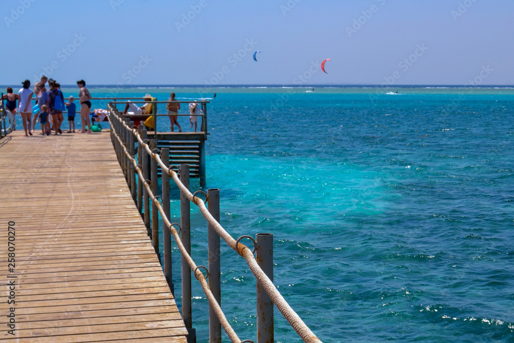 view from the pier at the people, the sea and skydivers
