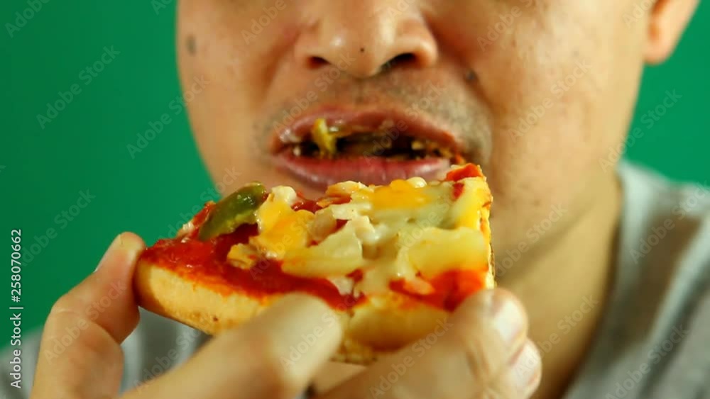 Thai man eating pizza with green background, in studio Chiangmai Thailand Thai man eating pizza with green background, in studio Chiangmai Thailand