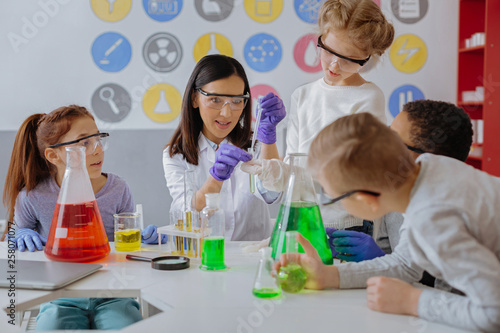 Dark-haired teacher dropping liquid in test tube