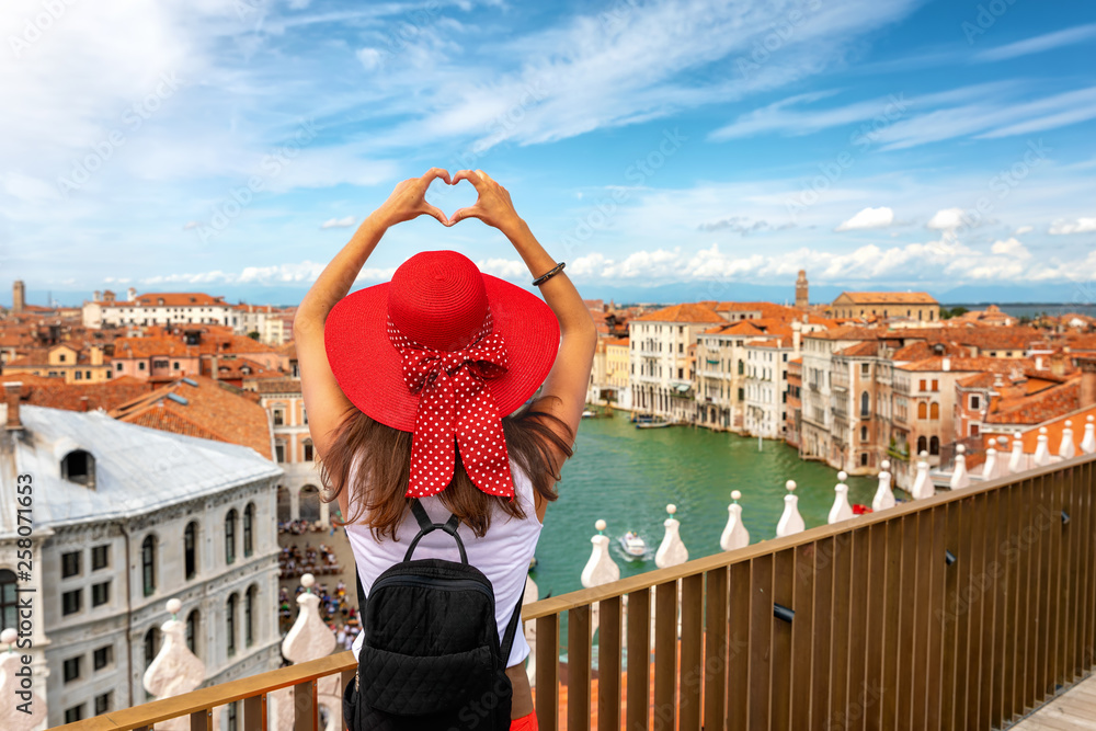 Touristin mit Sonnenhut formt ein Herz mit ihren Händen über den Dächern  von Venedig, Italien Stock Photo | Adobe Stock