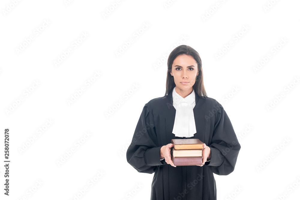 Serious judge in judicial robe holding books isolated on white Serious judge in judicial robe holding books isolated on white