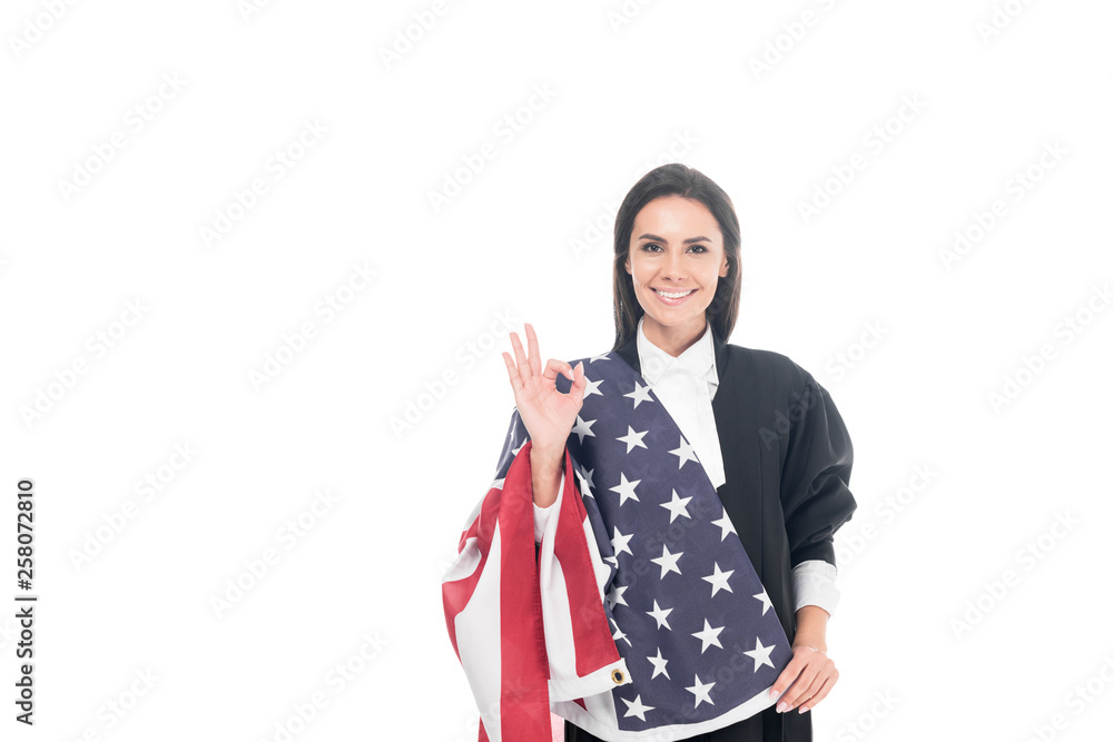 Smiling judge holding american flag and showing okay sign isolated on white