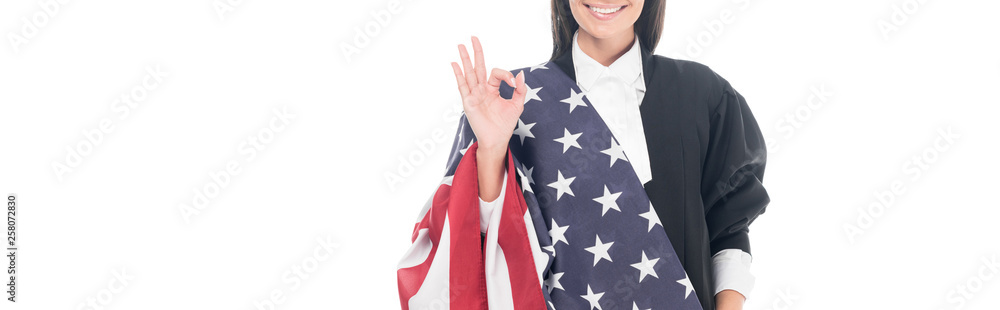 Obraz Panoramic shot of smiling judge holding american flag and showing okay sign isolated on white