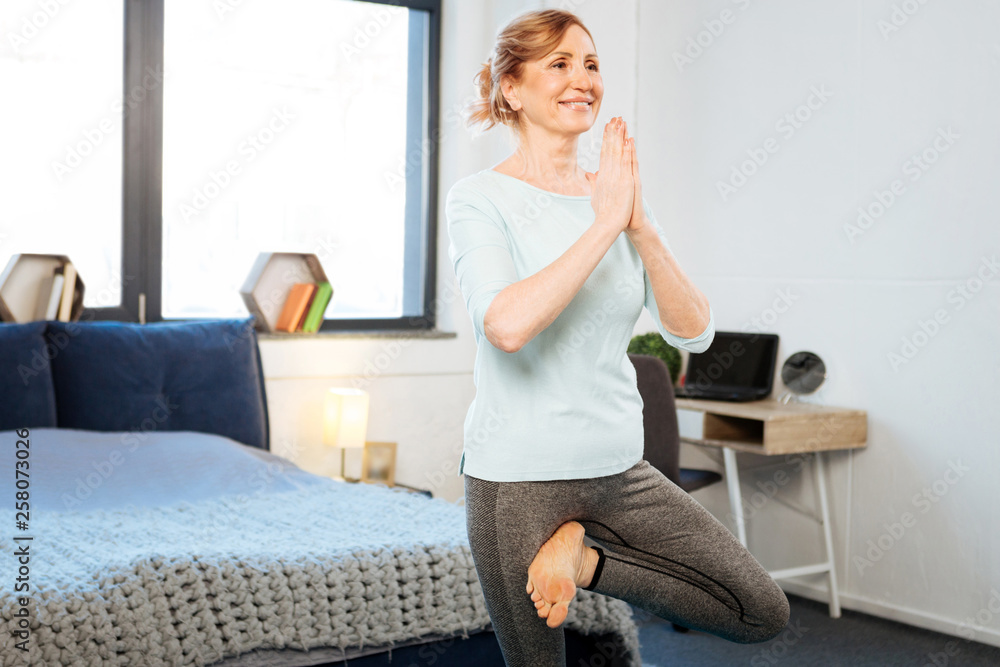 Beaming good-looking fit mature woman standing on one leg Beaming good-looking fit mature woman standing on one leg