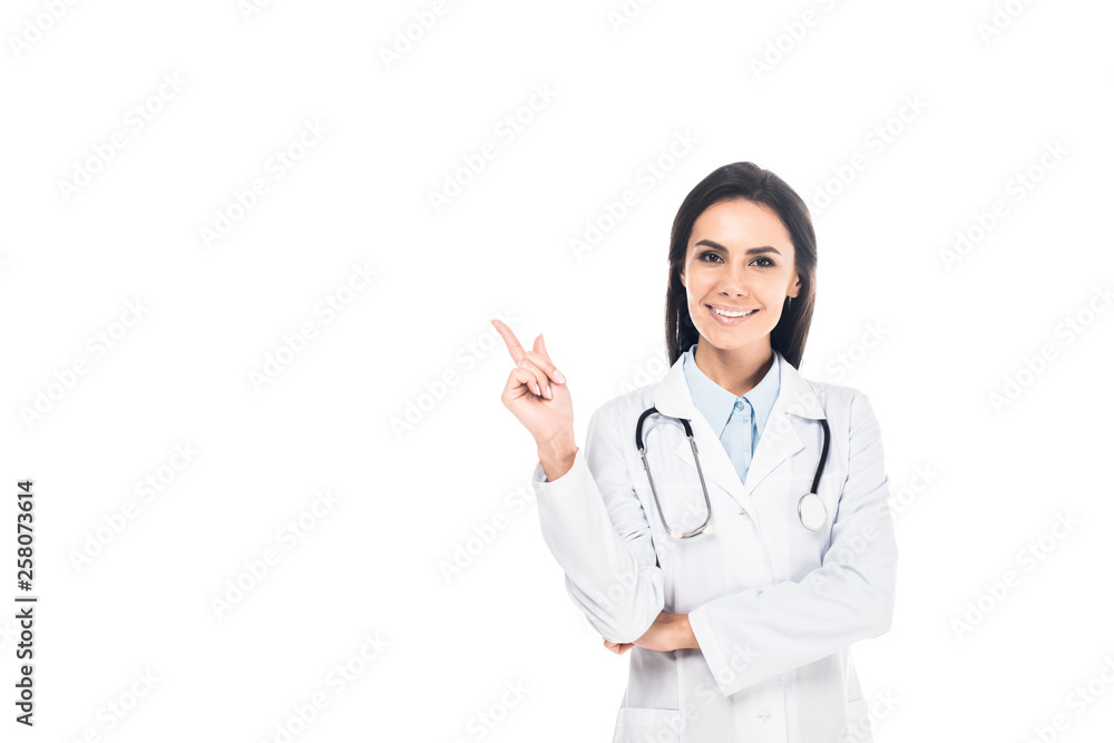 Smiling doctor in white coat with stethoscope pointing with finger isolated on white Smiling doctor in white coat with stethoscope pointing with finger isolated on white