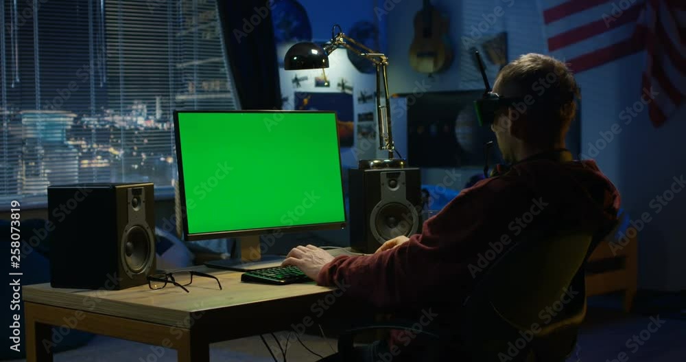 Man using a computer while wearing VR headset Man using a computer while wearing VR headset