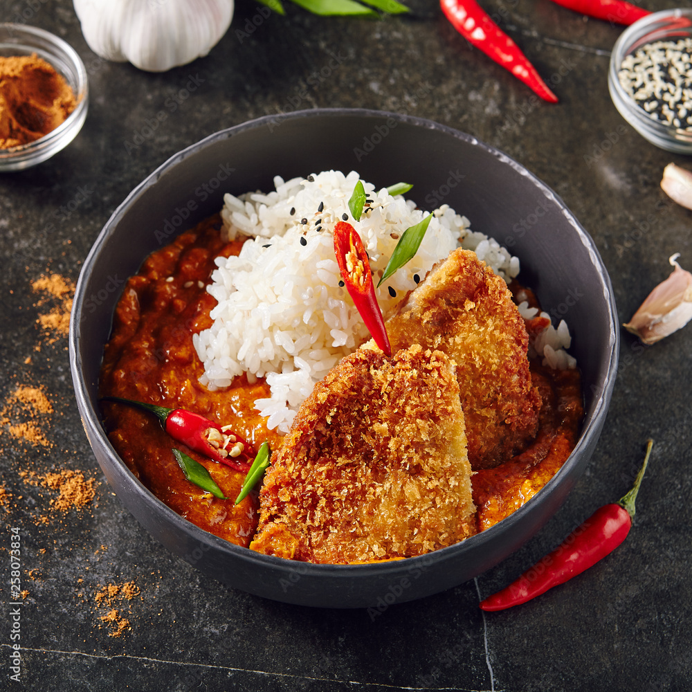 Hot Spicy Crispy Fried Pork Fillet with Curry and Rice on Dark Background Hot Spicy Crispy Fried Pork Fillet with Curry and Rice on Dark Background