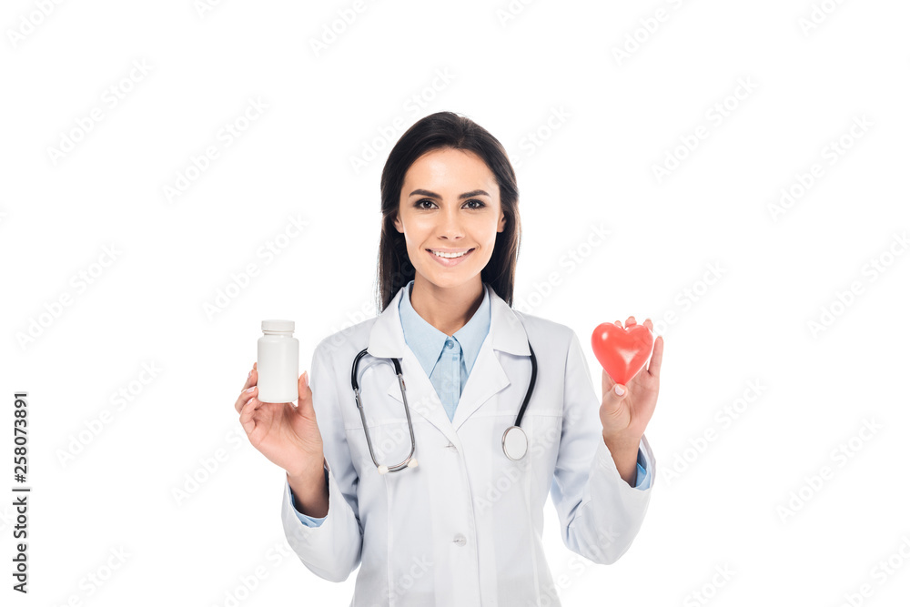 Doctor in white coat with stethoscope holding pills and plastic heart isolated on white Doctor in white coat with stethoscope holding pills and plastic heart isolated on white