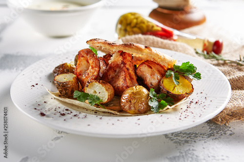 Grilled Pork with Potato, Spices and Pita Bread on Rustic Background