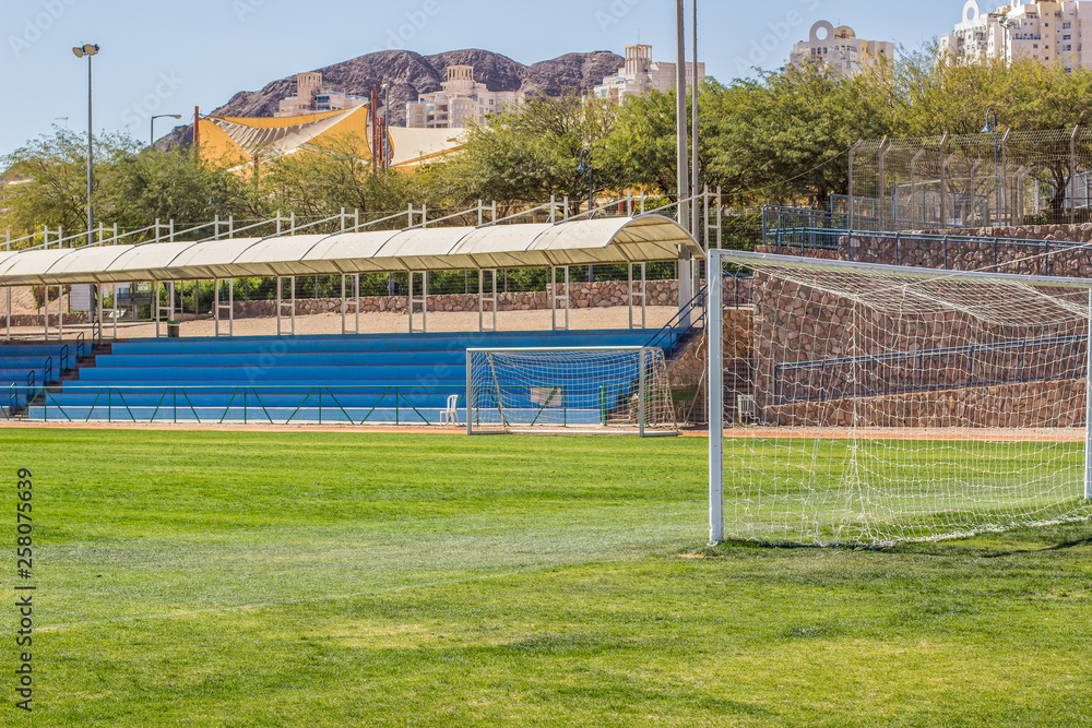 Fototapeta premium stadium complex football gates and grass field on empty blue tribune background, sport infrastructure concept, copy space