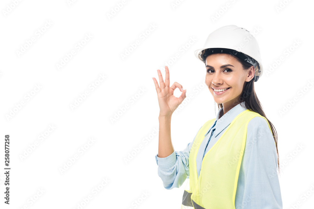 Smiling engineer in hardhat and safety vest showing okay sign isolated on white Smiling engineer in hardhat and safety vest showing okay sign isolated on white