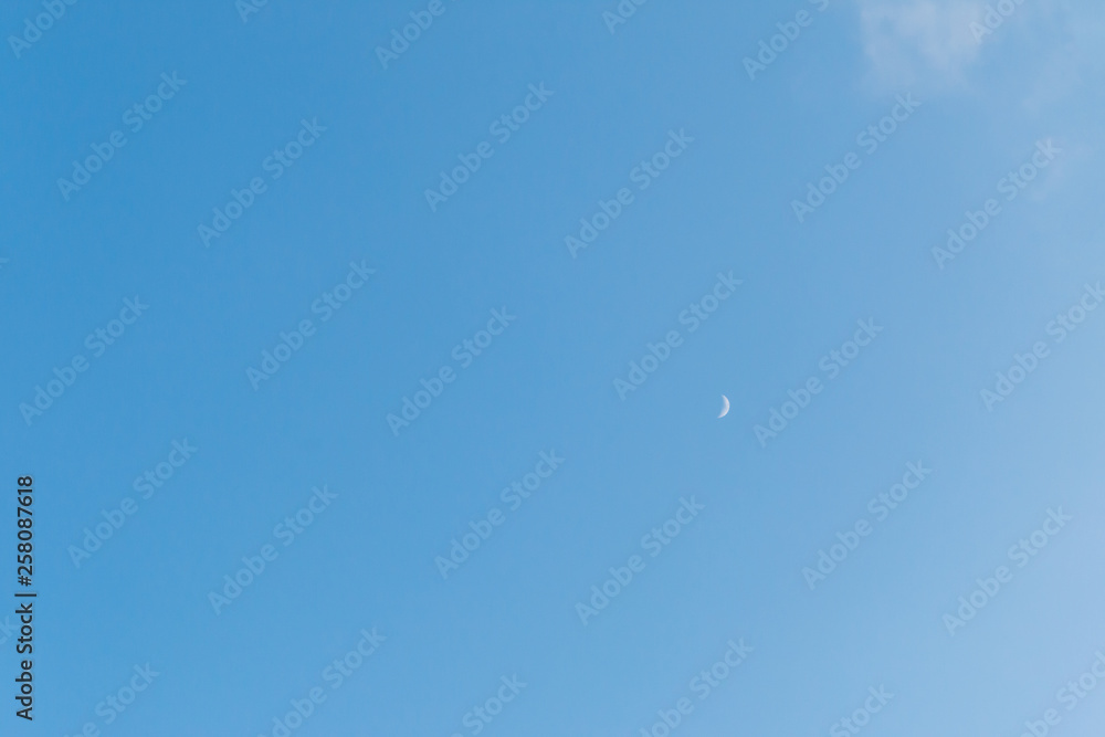 little evening moon on blue sky background, copy space for text. moon crescent on the clear sky background.