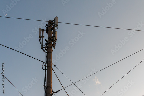 telecommunication pole with antennas and wires against the blue evening sky with a crescent, bottom view. Cell tower or Telecommunication tower. Wireless Communication Antenna Transmitter. Development