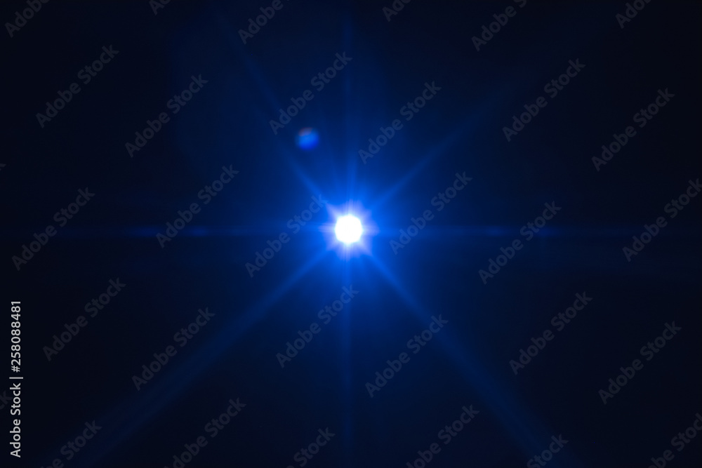 Single blue spark on black background. Lens flare effect. Defocused rays and lights.