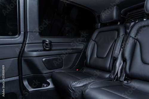 Сlose-up of the car black interior: rear seats and table with coasters.