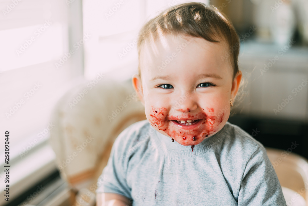 portrait of a child smiling with a dirty face in red jam portrait of a child smiling with a dirty face in red jam