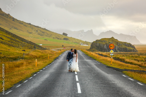young wedding couple, groom and bride walking on a road © hreniuca