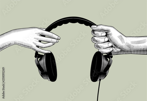 Hands of man and woman holding headphones
