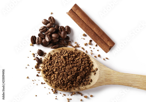 Instant coffee granules, beans and cinnamon stick with wooden spoon, isolated on white background, top view