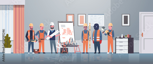 man architect engineer showing drawing building blueprint on easel board to construction workers group panning project team meeting presentation concept horizontal full length