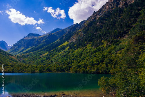 A huge panorama of the High-mountainous Baduk lake among the high Caucasian mountains and beautiful trees. Sunny summer day. © dmitriydanilov62