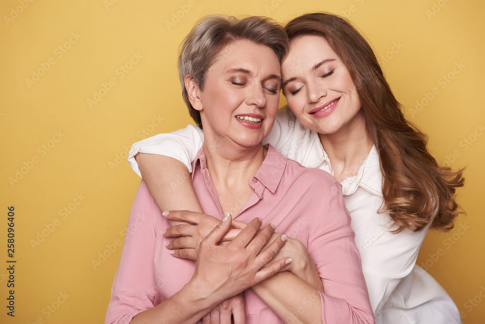Close up of beautiful woman with her charming daughter posing for camera Close up of beautiful woman with her charming daughter posing for camera