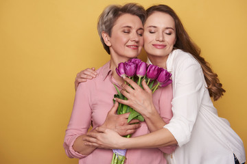 Beautiful Caucasian girl is hugging her mother while posing for camera