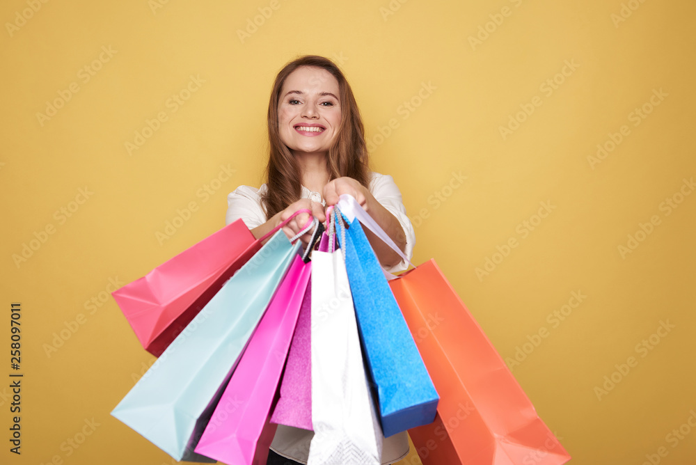 Waist up of Caucasian happy girl showing shopping bags for camera