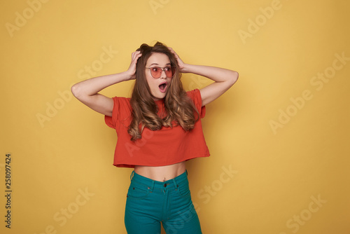 Waist up of surprised brunette young lady in eyeglasses posing for camera